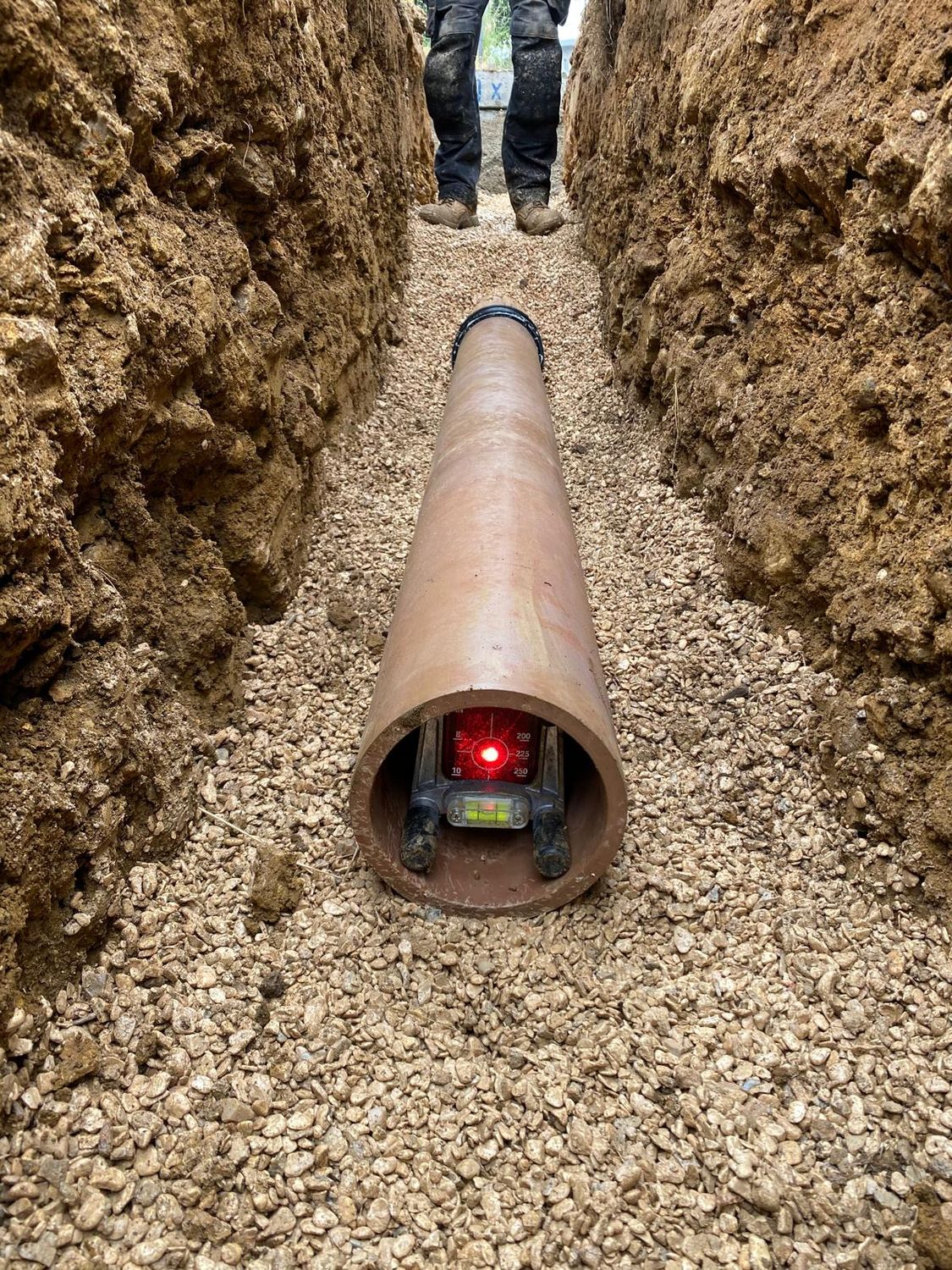 Pipe laser set up inside a pipe run on a gravel bed