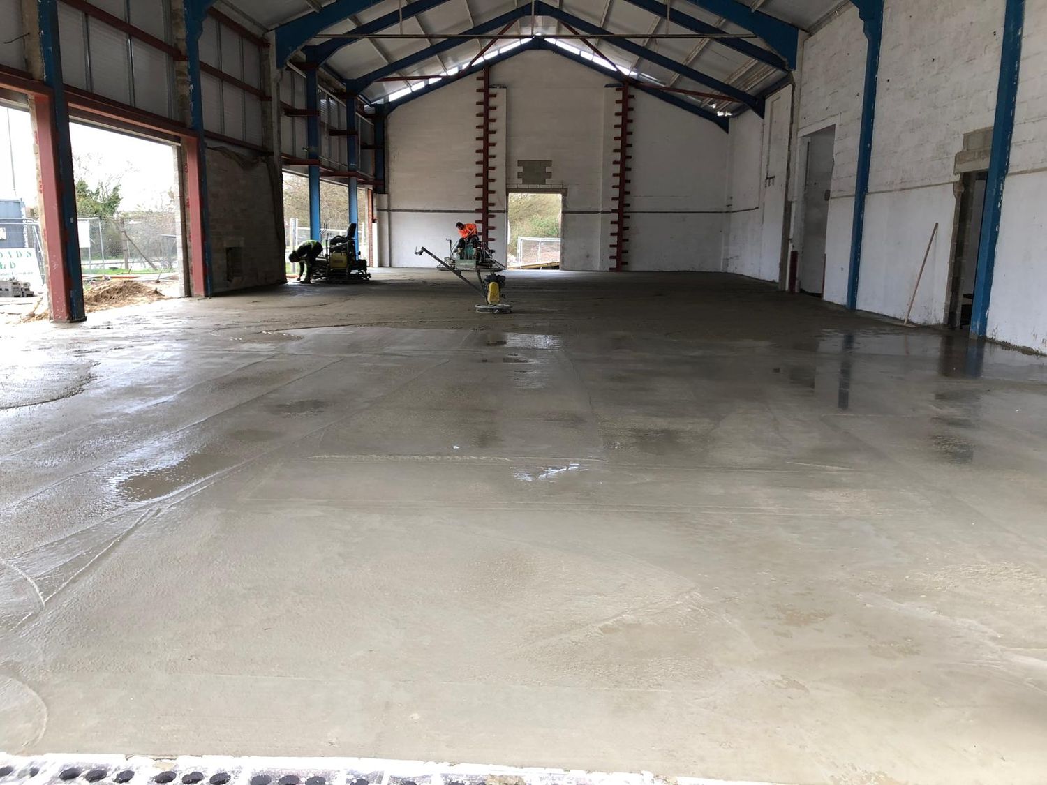 Floor slab being finished inside a steel framed building